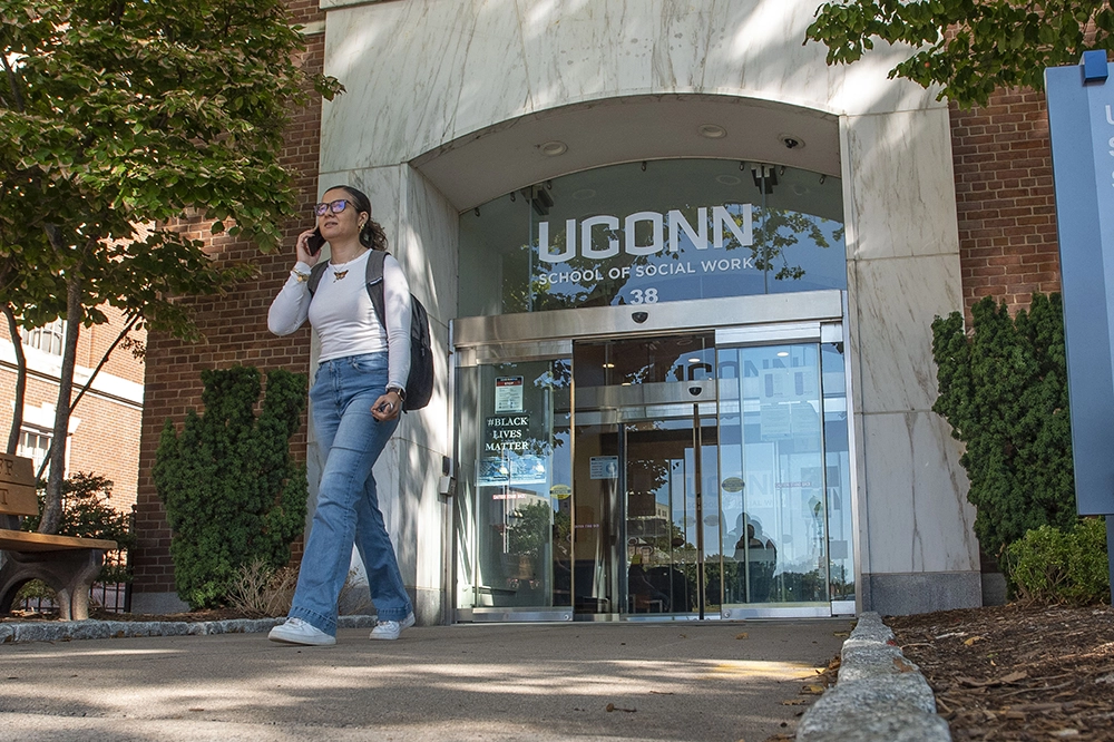 Student walking out of UConn School of Social Work